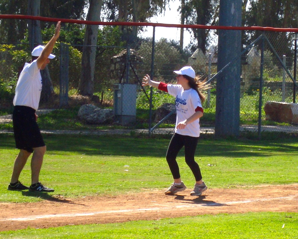 Coach and player high-five on baseball field
