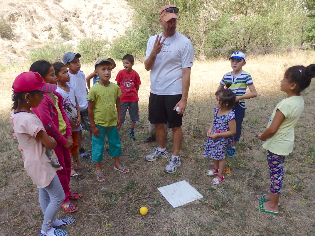 Coach instructing children with baseball base and ball